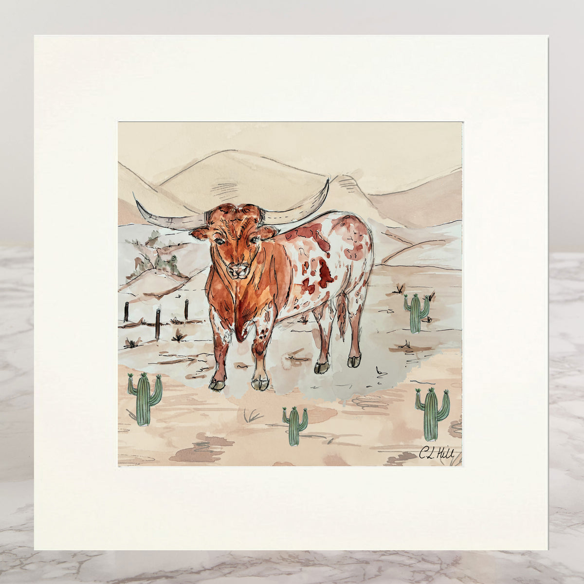 A matted art print featuring a watercolor-style illustration of a longhorn steer in a desert landscape with cacti and mountains. The print has a wide white mat border and is photographed against a light gray background with a marble surface visible at the bottom.