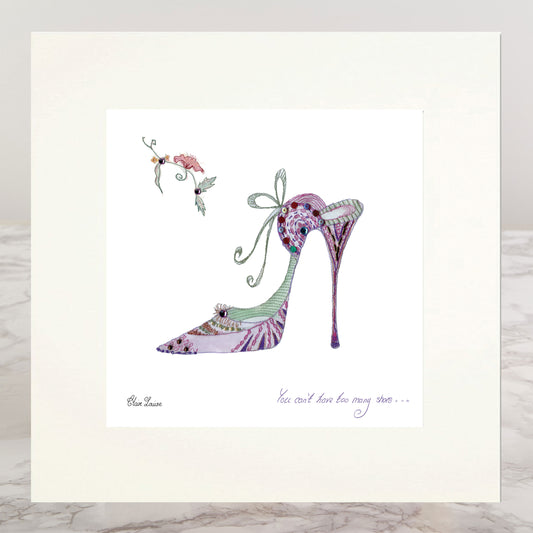 A matted art print featuring a whimsical watercolor illustration of a high-heeled shoe in lavender, purple, and green, with a small bird and the quote 'You can't have too many shoes' by Blue Mean.