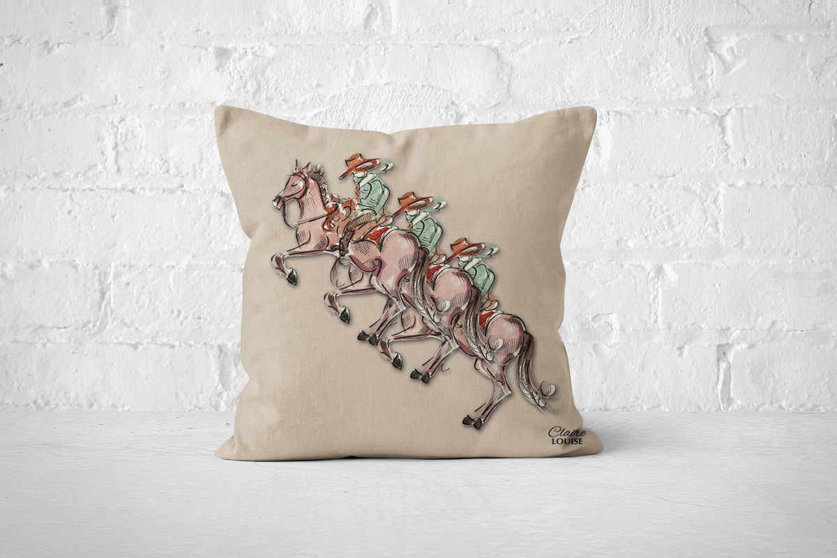 A square beige throw pillow featuring an illustration of three cowboys.