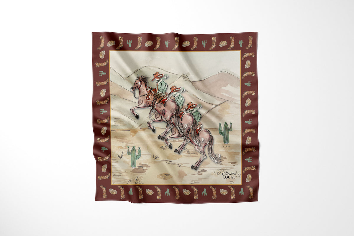 A square silk scarf featuring a western desert illustration with three cowboys, cacti, and a brown border patterned with small motifs, shown against a plain white background.