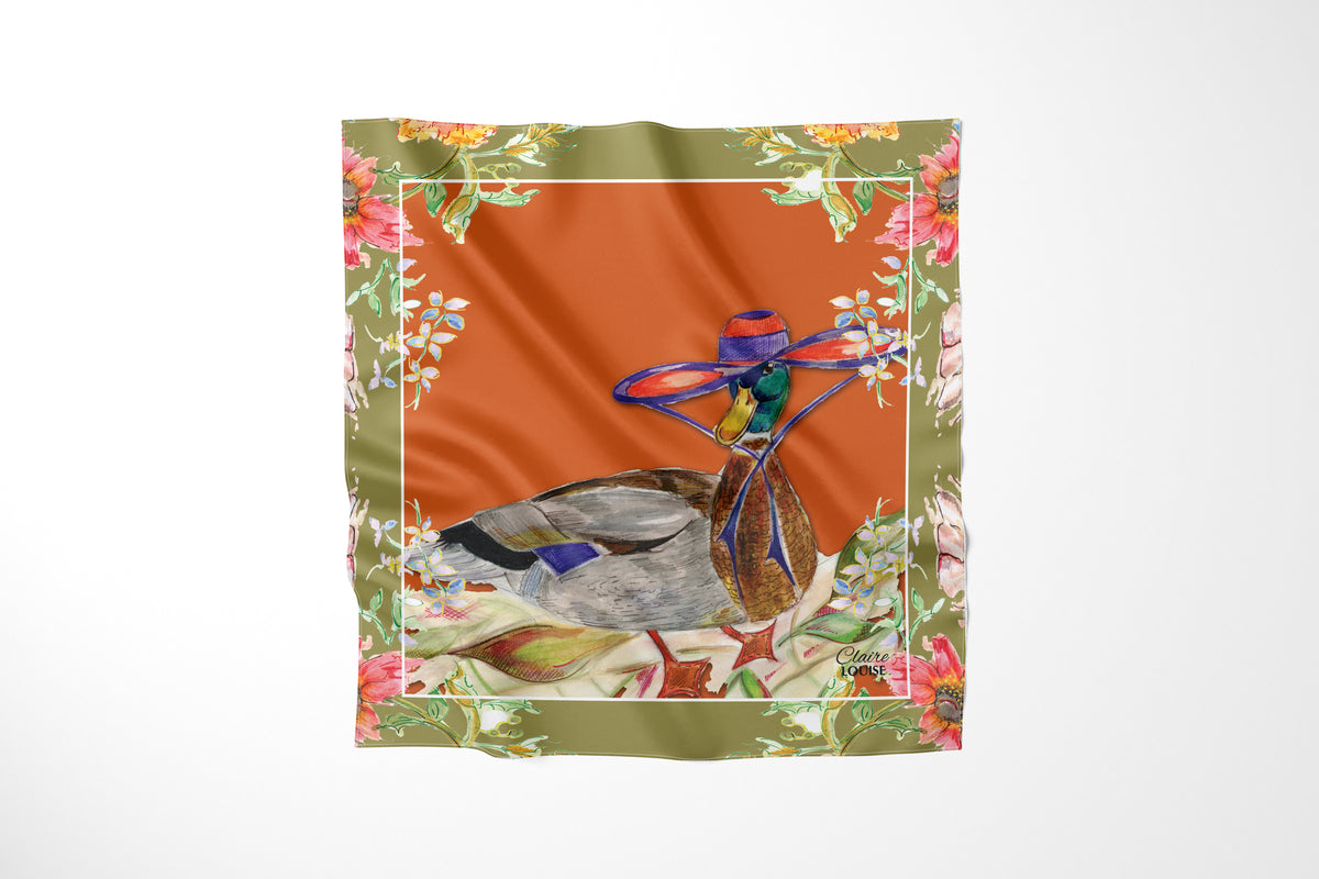 Whimsical Duck Scarf by Claire Louise, a mallard in a wide-brimmed purple hat on burnt orange with an olive floral border