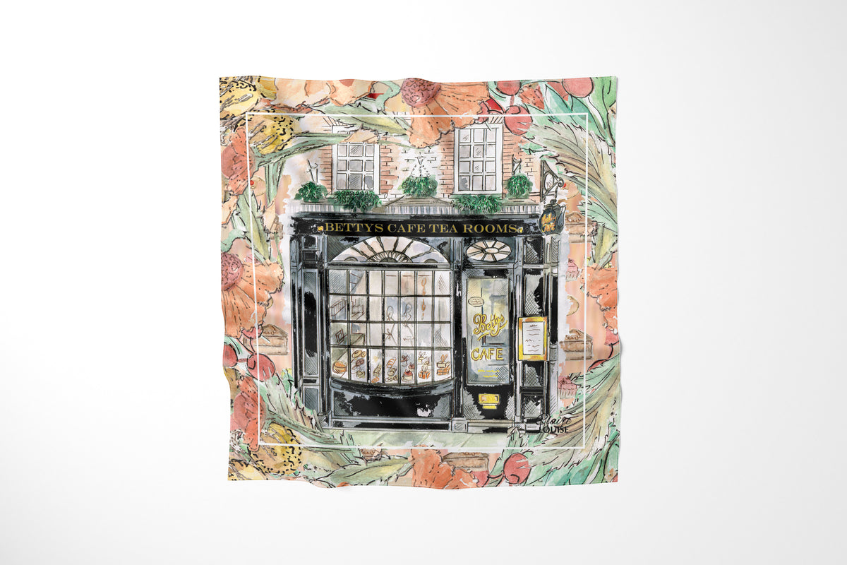 Bettys In Full Bloom Scarf by Claire Louise: watercolour of the black Bettys Cafe Tea Rooms shopfront framed by peach flowers and green foliage