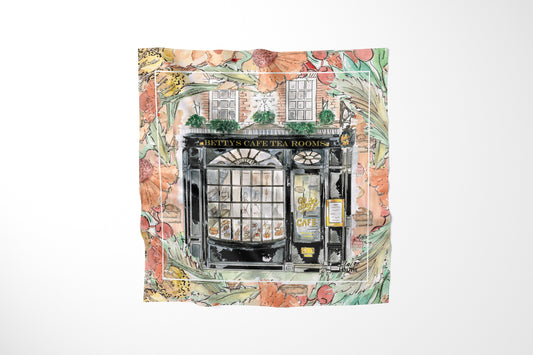 Bettys In Full Bloom Scarf by Claire Louise: watercolour of the black Bettys Cafe Tea Rooms shopfront framed by peach flowers and green foliage